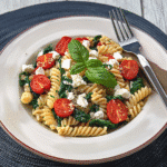 Serving pasta with spinach and tomatoes and feta